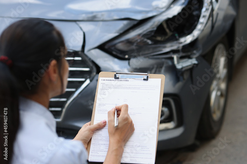 Фотография Woman insurance agent fills out insurance form for car damage after traffic acci