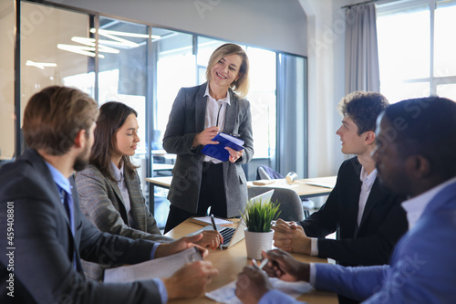 Quadro su tela Female boss addressing meeting around boardroom table.
