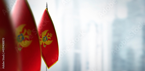 Small flags of Montenegro on a blurry background of the city