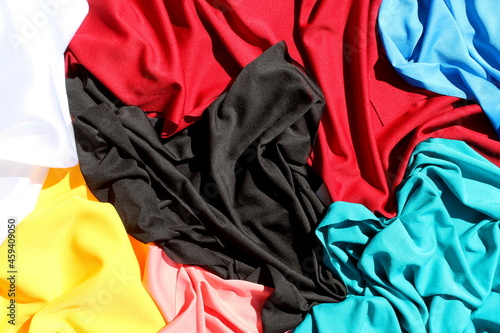 A bunch of different bright, multi-colored fabrics lie in one heap.