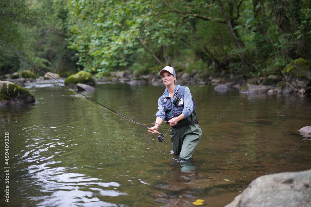 young woman fly fishing in a mountain river