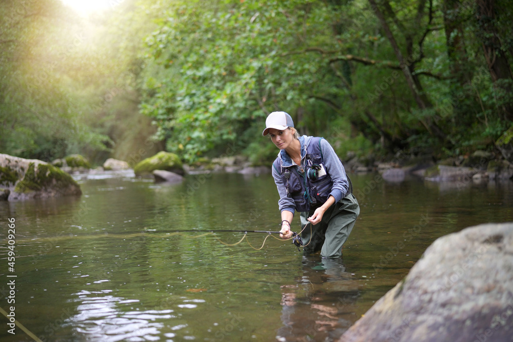 young woman fly fishing in a mountain river young woman fly fishing in a mountain river