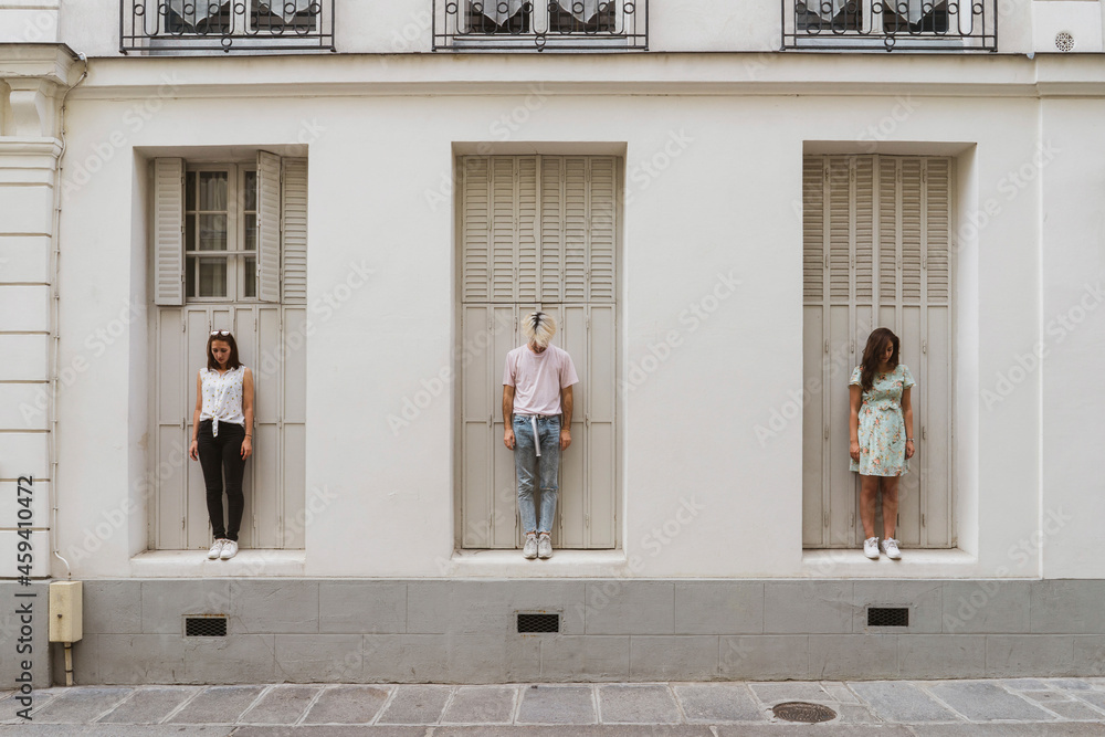 Young man and women looking down while standing in front of wall Young man and women looking down while standing in front of wall