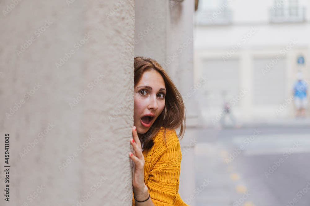Surprised woman with brown hair peeking from wall Surprised woman with brown hair peeking from wall