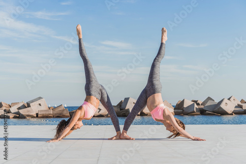 Female acrobats practicing Urdhva Prasarita Eka Padasana on boardwalk photo