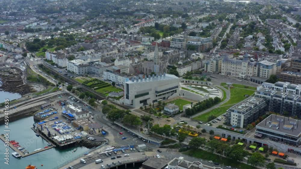 Lexicon, Dún Laoghaire, Dublin, Ireland, September 2021. Drone slowly orbits and pushes towards the modern library building surrounded by a coastal town. Lexicon, Dún Laoghaire, Dublin, Ireland, September 2021. Drone slowly orbits and pushes towards the modern library building surrounded by a coastal town.
