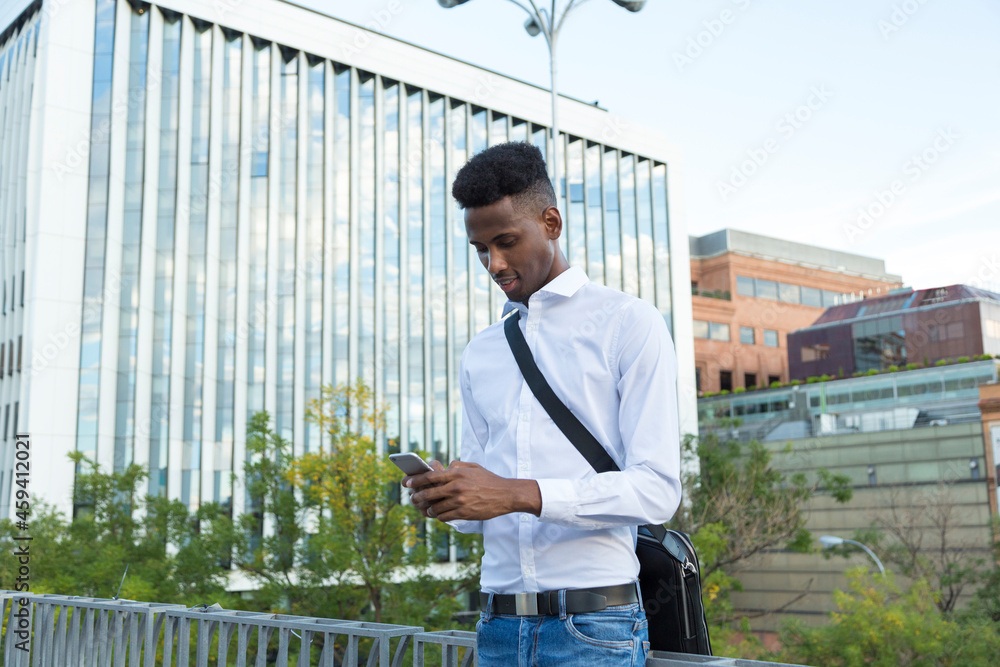 Young African American businessman in white shirt and briefcase writing a message on the phone on the street Young African American businessman in white shirt and briefcase writing a message on the phone on the street