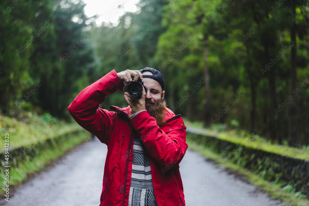Young male tourist photographing through camera while standing on road Young male tourist photographing through camera while standing on road