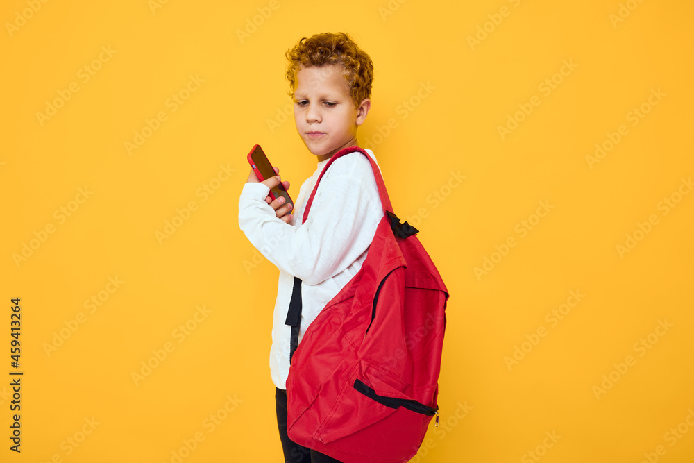 joyful schoolboy with a red backpack calls on the phone Studio learning concept joyful schoolboy with a red backpack calls on the phone Studio learning concept