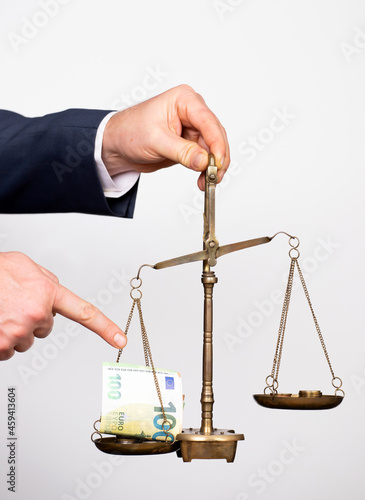 Money weighing on justice scale in business man hand. Payment balance and tax