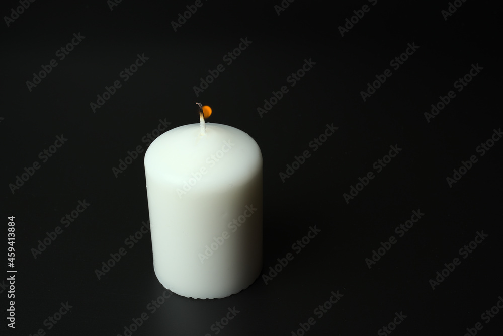 A large white burning candle on a black background A large white burning candle on a black background