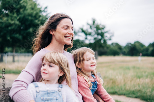 Smiling mother sitting with daughters at public park