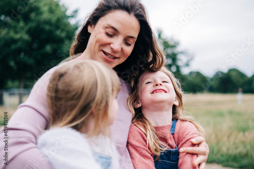 Smiling woman talking with girls at park photo