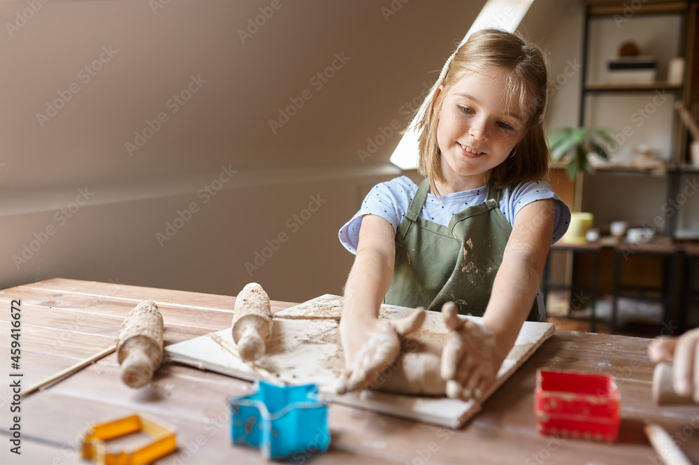 Obraz premium Little girl works with forms for clay at the table