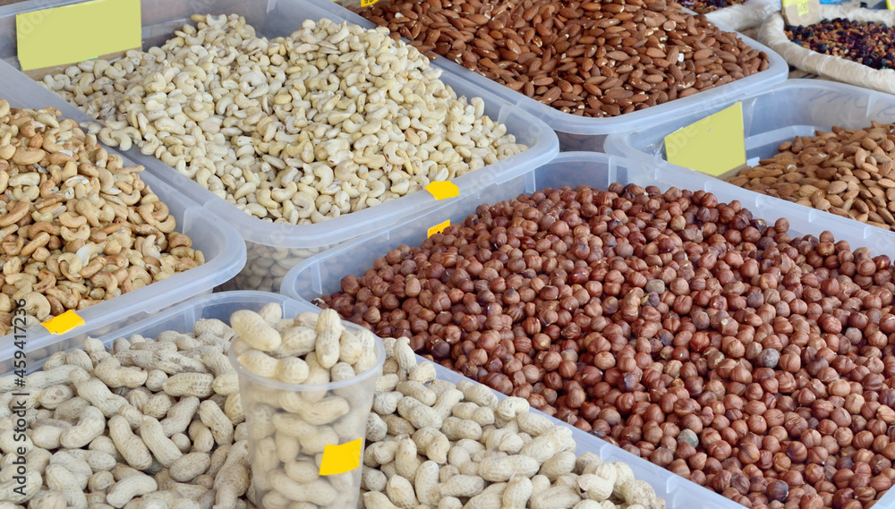 Fototapeta premium pistachios, almonds, cashews, hazelnuts are in plastic containers for sale