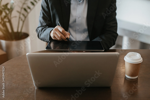 Male businessman working with tablet and laptop at cafe in the morning.