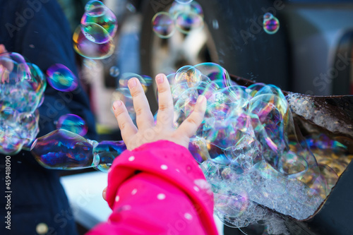 a child's hand reaches for a lot of soap bubbles