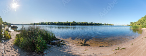 Panorama of river with sandy and forested banks in summer