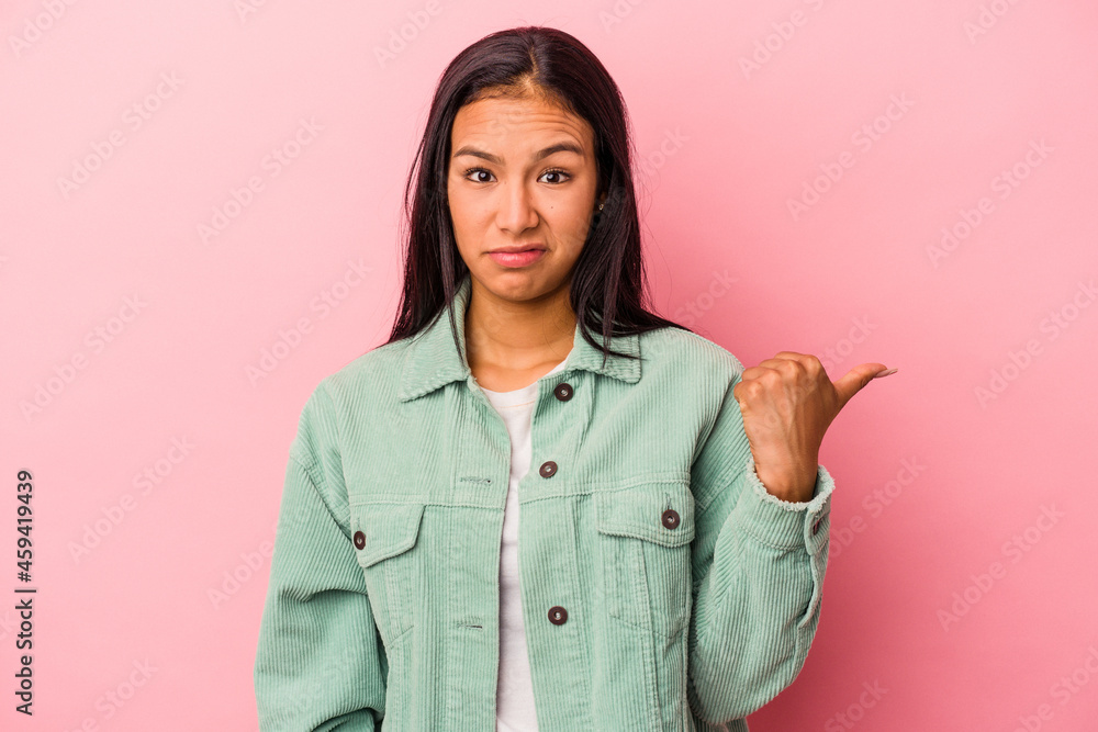 Young latin woman isolated on pink background shocked pointing with index fingers to a copy space. Young latin woman isolated on pink background shocked pointing with index fingers to a copy space.