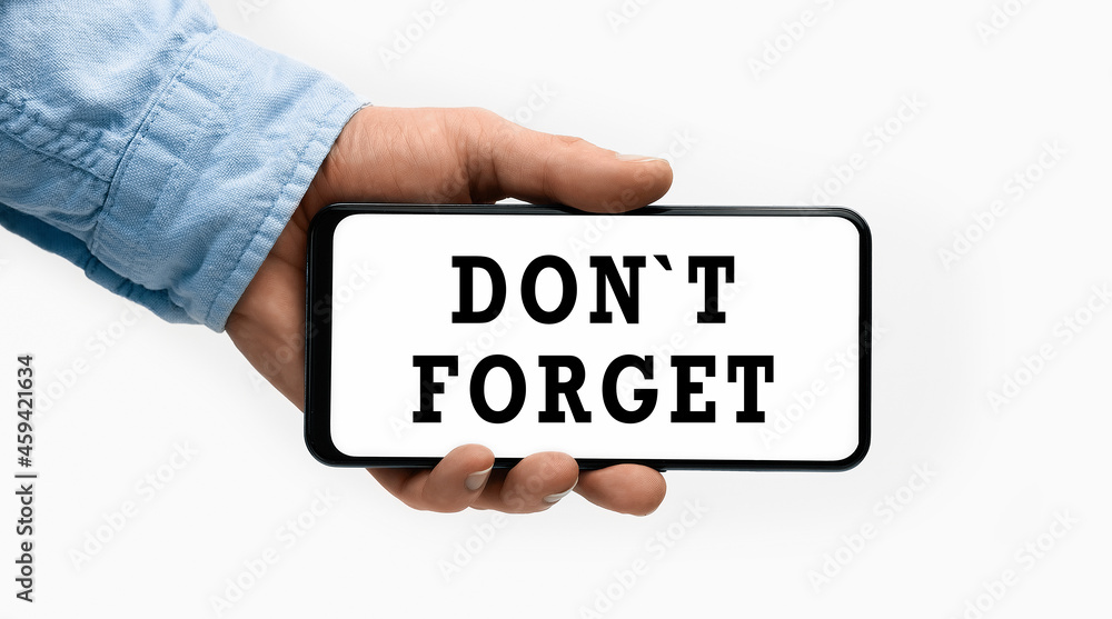 Closeup of a male hand holding Smartphone with horizontal text DonT Forget on display Closeup of a male hand holding Smartphone with horizontal text DonT Forget on display