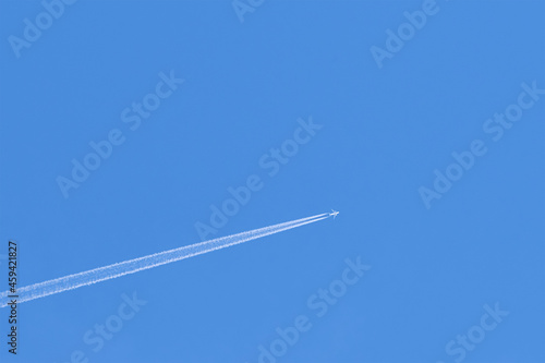 Plane trail on clear blue sky. Copyspace.