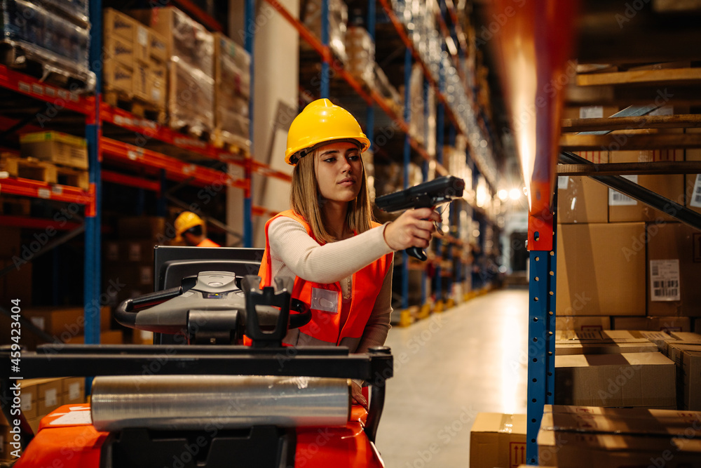 Woman working with bar-code reader in warehouse
