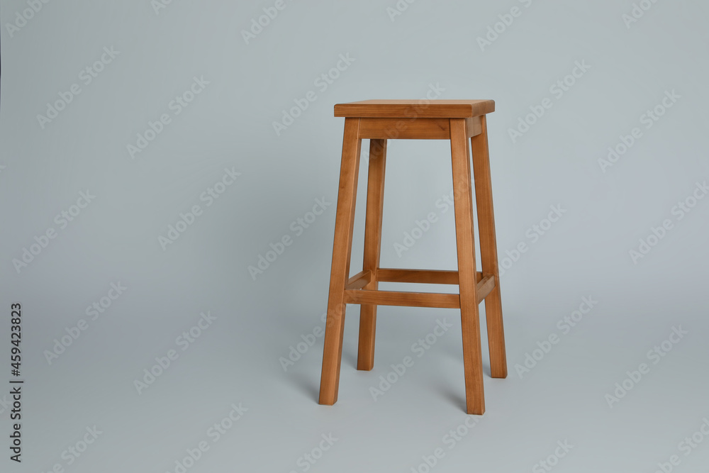 Stylish wooden stool on light grey background. Space for text Stylish wooden stool on light grey background. Space for text