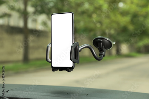 Car holder with modern mobile phone on windshield of automobile. Mockup for design photo