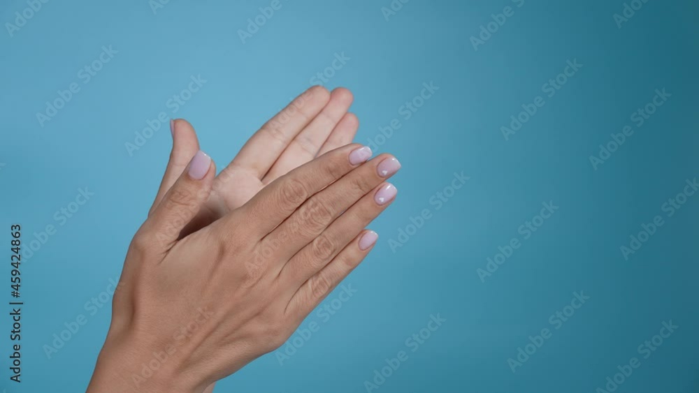 Close-up 4k slow motion video of two beautiful manicured female hands applauding happily isolated on blue wall background Close-up 4k slow motion video of two beautiful manicured female hands applauding happily isolated on blue wall background