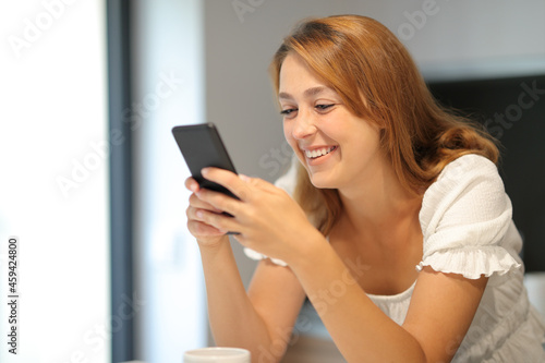 Happy woman using smart phone smiling at home