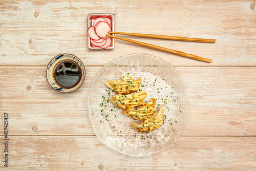 top view image of serving of gyozas with sauce and chives, chopsticks, radishes and soy sauce photo