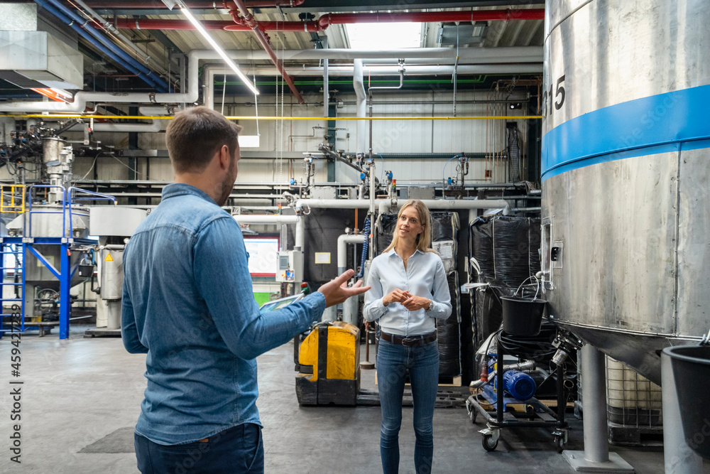 Male professional explaining colleague while standing at factory Male professional explaining colleague while standing at factory