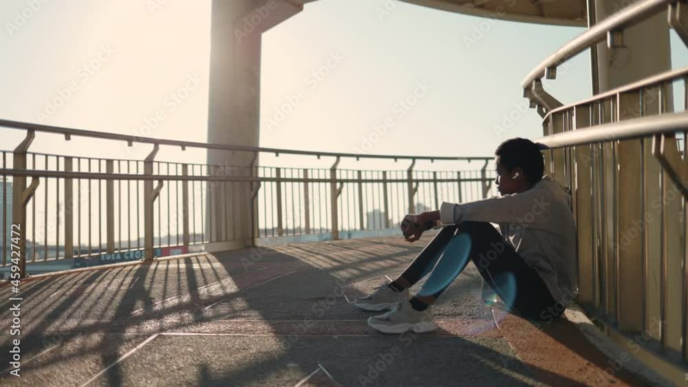 African american woman sitting on bridge while resting after run African american woman sitting on bridge while resting after run