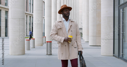 Handsome african american entrepreneur walking with coffee cup outdoors