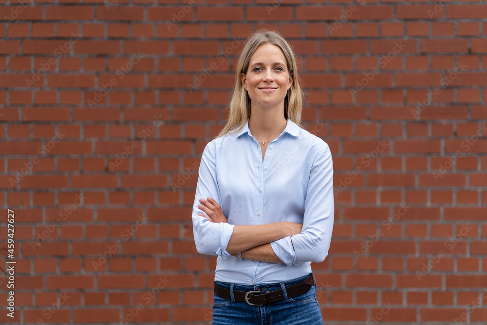 Smiling businesswoman with arms crossed standing in front of wall Smiling businesswoman with arms crossed standing in front of wall