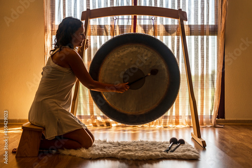 Sound healerl playing gong while sitting by window