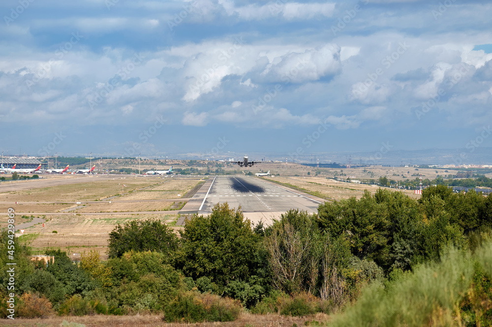 Runway and terminal of Madrid Barajas airport, in which we can see an Airbus A321 of the Iberia Express airline taking off with a cloudy sky