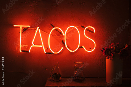 Glowing red sign with tacos written on the wall