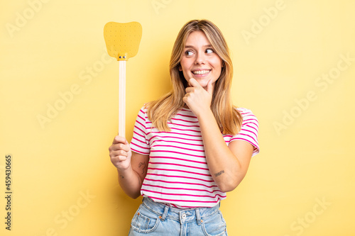 pretty blonde girl smiling with a happy, confident expression with hand on chin. kill flies concept