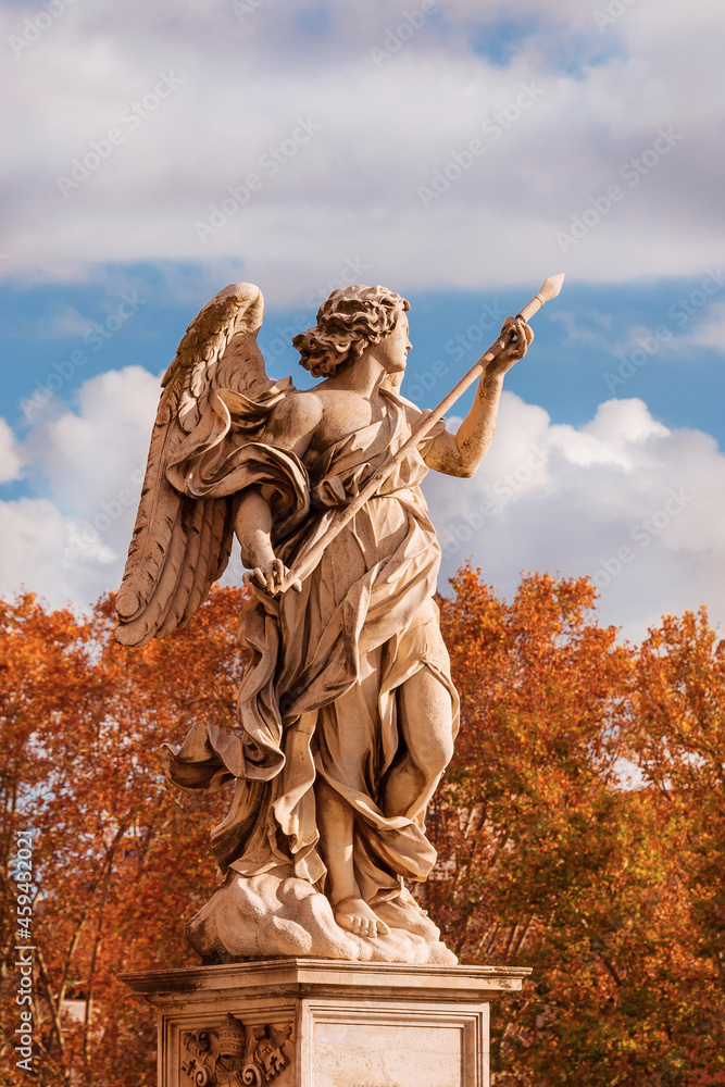Autumn in Rome. Beautiful angel statue with Holy Lance of Longinus at the top of Sant'Angelo Bridge, erected in the 17th century, with atumnal leaves in the background