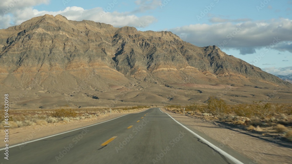 Road trip, driving auto from Death Valley to Las Vegas, Nevada USA. Hitchhiking traveling in America. Highway journey, dramatic atmosphere, clouds, mountain and Mojave desert wilderness. View from car