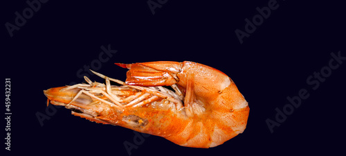 On a dark background, there is a large roll-off shrimp. Beautiful, juicy shrimp. Ukraine 2021.