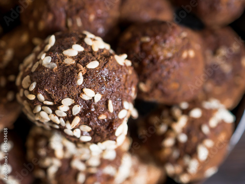Close-up brown.vegetarian sweets garnished with sesame seeds and carob powder. Energy balls. Raw food sweets. Proper nutrition.