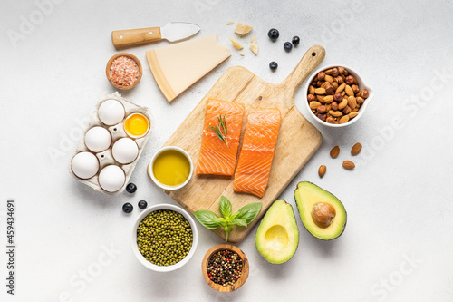 Assortment of healthy protein sources and body building food : fish, vegetables, legumes, nuts, cereals and dairy products on a light slate, stone or concrete background. Top view, copy space