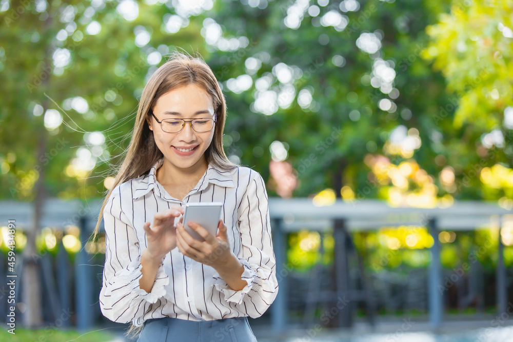 Asian business woman happy smiling looking at smartphone standing park outdoor green nature background Asian business woman happy smiling looking at smartphone standing park outdoor green nature background