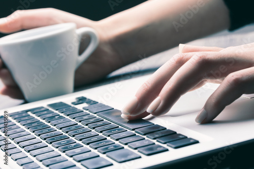 woman hands on laptop keyboard and cup of coffee