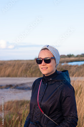Pretty smiling confident woman in gray headband walking on sea background lifestyle real life travel photo. Millennial hipster girl smiling relaxing outdoor. Generation Z casual female casual portrait © KawaiiS