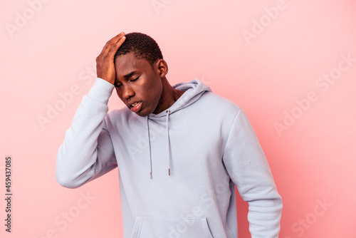 Young African American man isolated on pink background forgetting something, slapping forehead with palm and closing eyes. © Asier