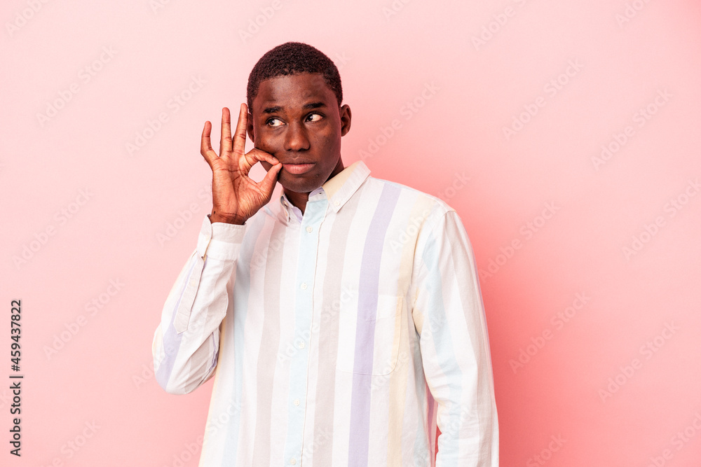 Young African American man isolated on pink background with fingers on lips keeping a secret. Young African American man isolated on pink background with fingers on lips keeping a secret.