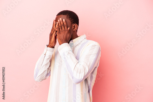 Young African American man isolated on pink background afraid covering eyes with hands.